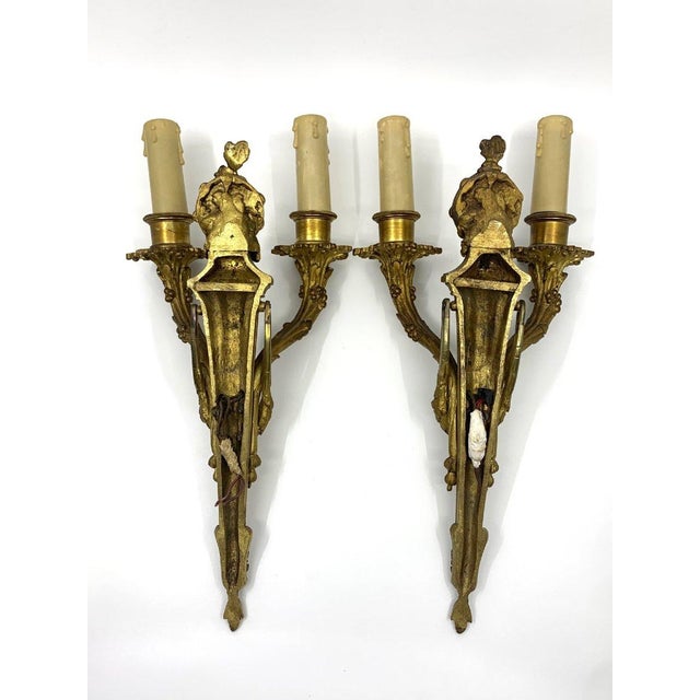 After Jean-Charles Delafosse, a pair of gilt bronze rocaille wall sconces. Decorated with rocaille motifs and garlands....