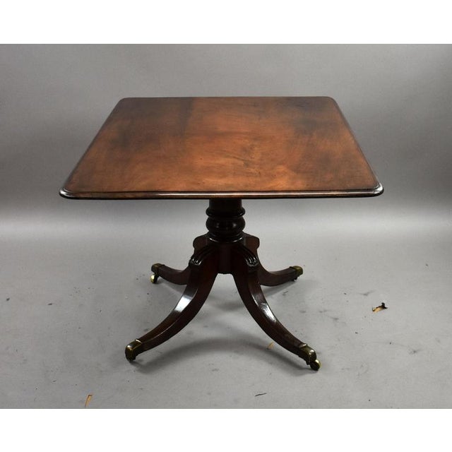 A handsome Regency mahogany breakfast table, featuring a rectangular tilt-top with rounded corners and a moulded edge. The...