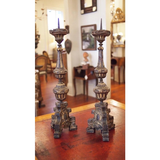 A pair of late 17th, early 18th century repousse tole candlesticks, each pedestal base on three feet and supporting an urn...