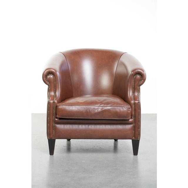 This beautiful and comfortable cognac-coloured cowhide leather club armchair in English style features a loose seat...