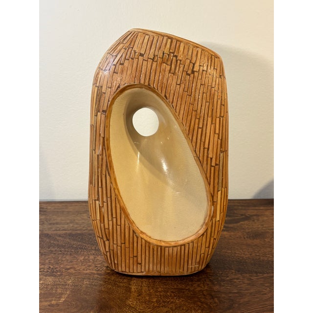 A sculptural vintage coastal vessel marrying organic modern form with hand-worked natural material. The cream glazed...