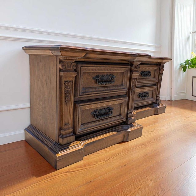 A substantial pair of traditional wood nightstands with architectural moldings, carved scroll details, paneled drawer...