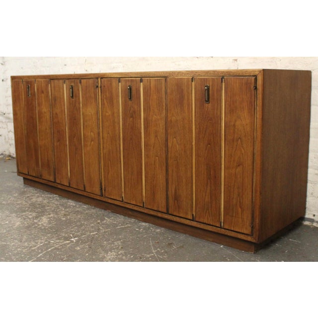 This walnut credenza is apart of Broyhill Premier's Modern Classic collection. The credenza features a vibrant grain...