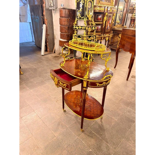An elegant French Louis XVIstyle rolling serving table / étagère trolley, combining warm mahogany tones, delicate floral...