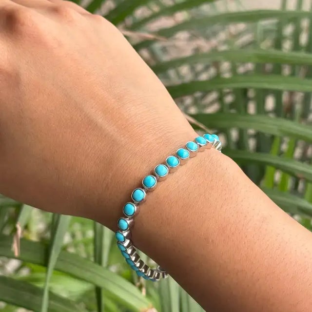 This stunning tennis bracelet is crafted in 925 sterling silver and set with 31 cushion-cut turquoise gemstones, each...
