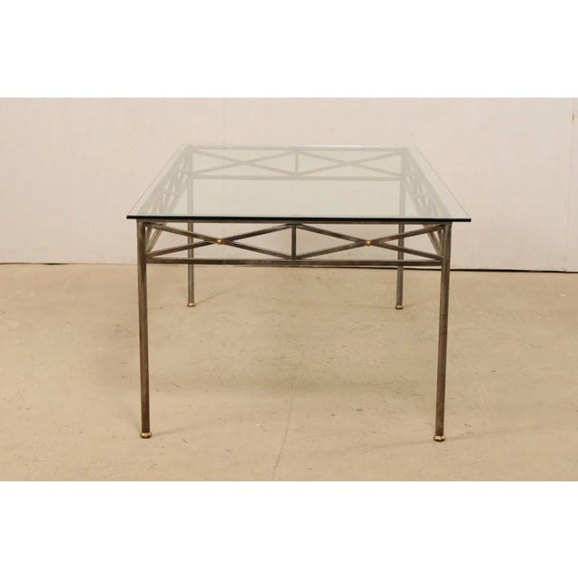 An American-made rectangular-shaped glass top table from the late 20th century. This vintage table has a Neoclassical...