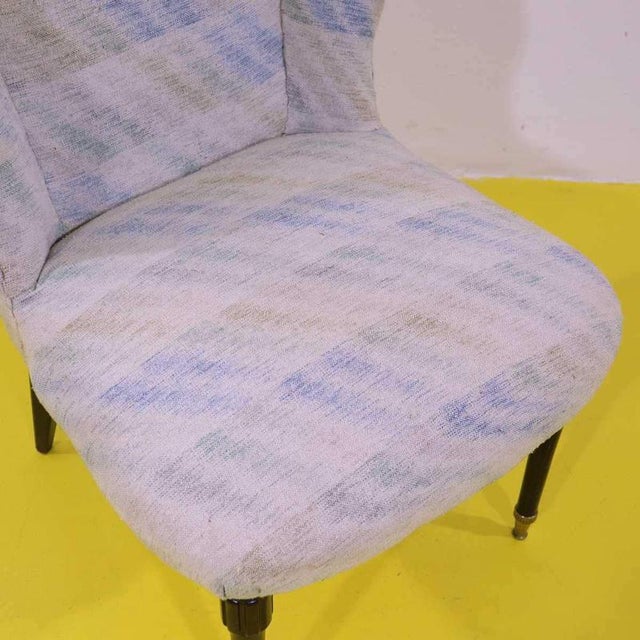 Light patterned fabric armchair with wooden legs and tips.