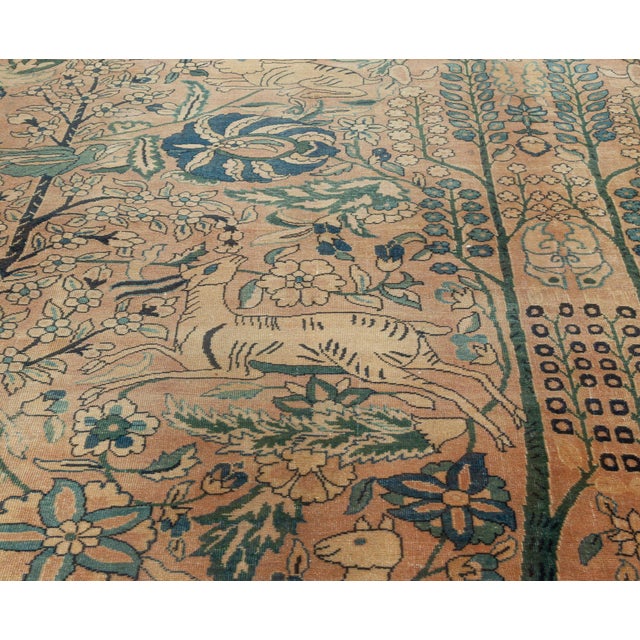 An early 20th century Persian Kirman (Kerman) antique carpet, the dusty pink field with an allover pattern of exotic...