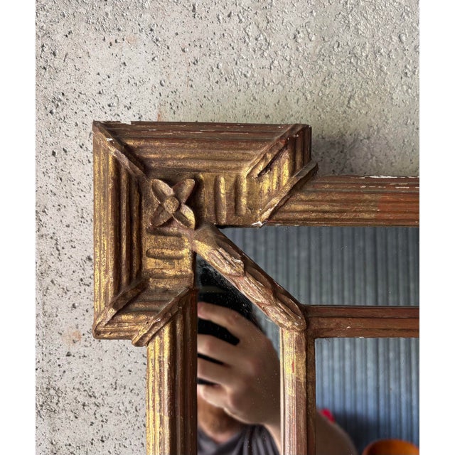 An elegant vintage Hollywood Regency wall mirror featuring a richly gilt frame with crisp geometric detailing and...