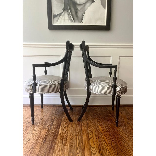 A pair of beautiful, vintage Federal style arm chairs. This pair of matching chairs includes a straight crest rail with...