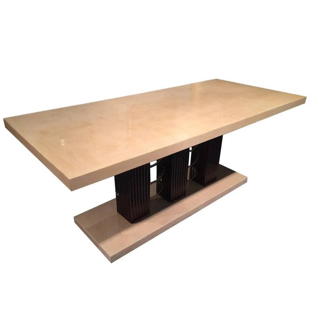 This Art Deco table, with a top and base in parchment veneer, has column legs with brass decorations.