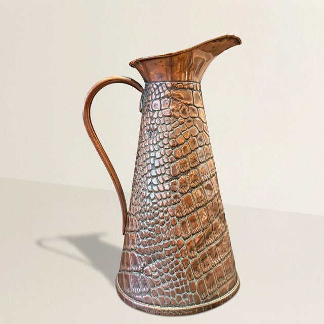 This early 20th-century English Arts & Crafts copper vessel leans closer to object than accessory—its surface relentlessly...