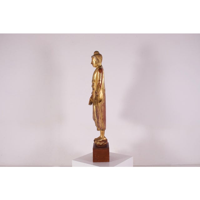 The standing buddha, carved in solid wood on its lotiform base, burma, early mandalay period, mid-19th century. The...