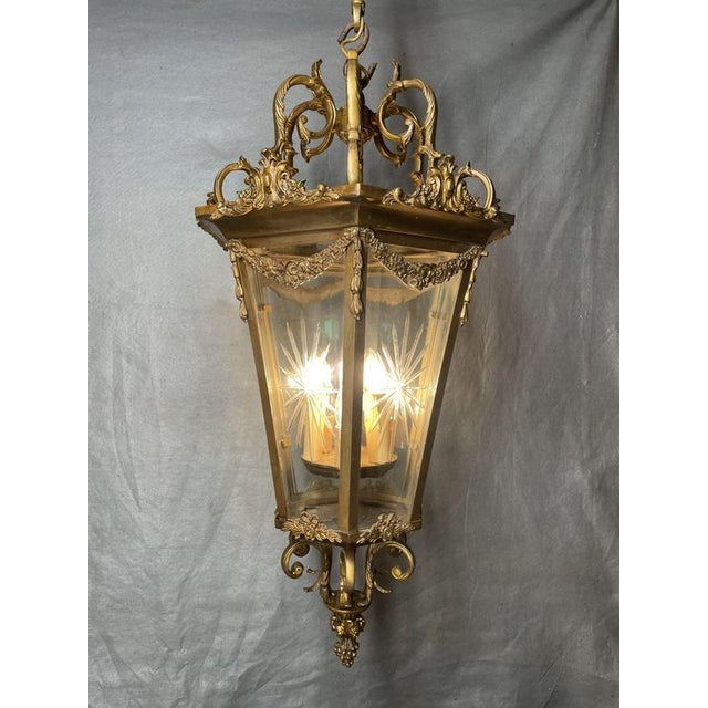 A large French gilded bronze hall lantern with three light fittings and eight beveled glass panels, each featuring a star-...