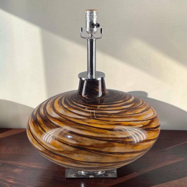The Mid-Century Modern Art Glass Brown Swirl Lucite Base Table Lamp is a stylish and unique lighting piece perfect for...
