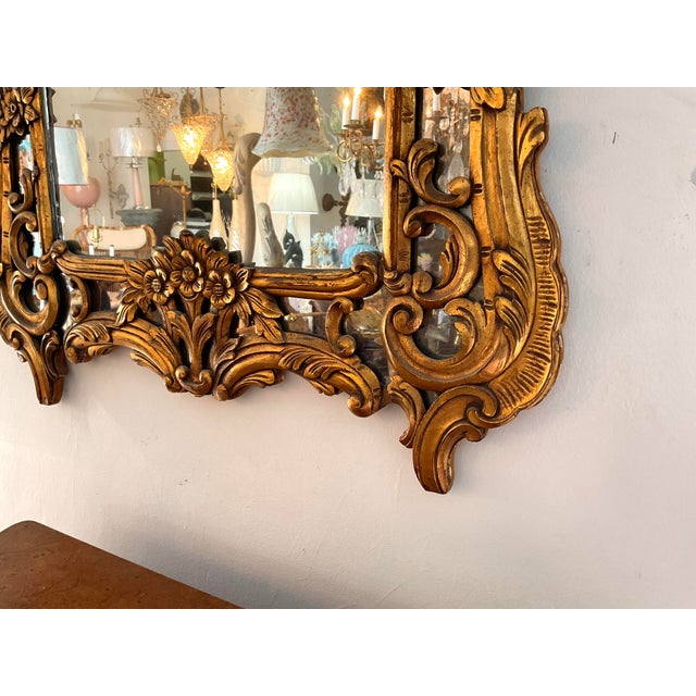A magnificent Italian Baroque style wall mirror, exquisitely hand-carved in solid wood and finished in a rich antiqued gilt.