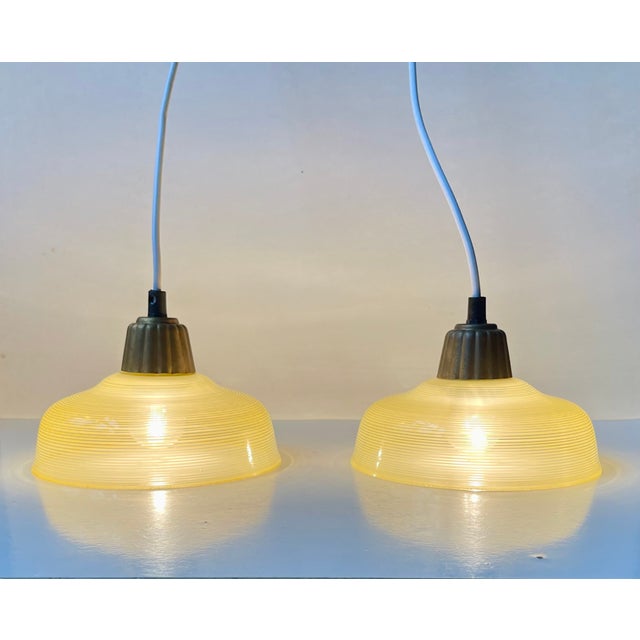 Art Deco or Bauhaus era styled hanging lamps featuring striped yellow/clear hand-blown glass shades and fluted tops in...