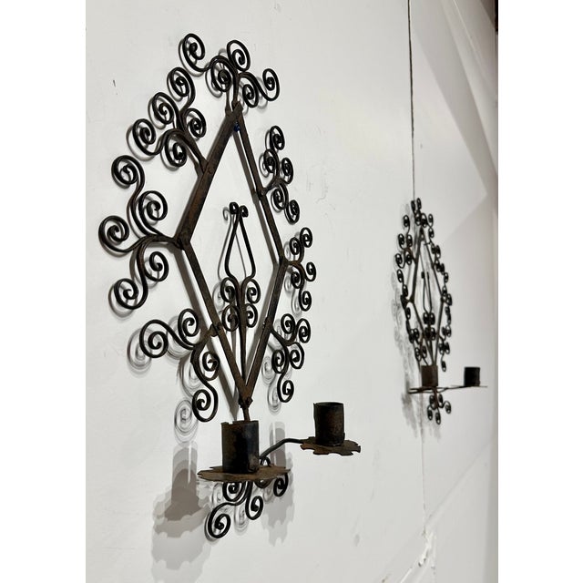Vintage Mid Century wrought iron candle sconce pair. Filigree design and two candle holders on each sconce.