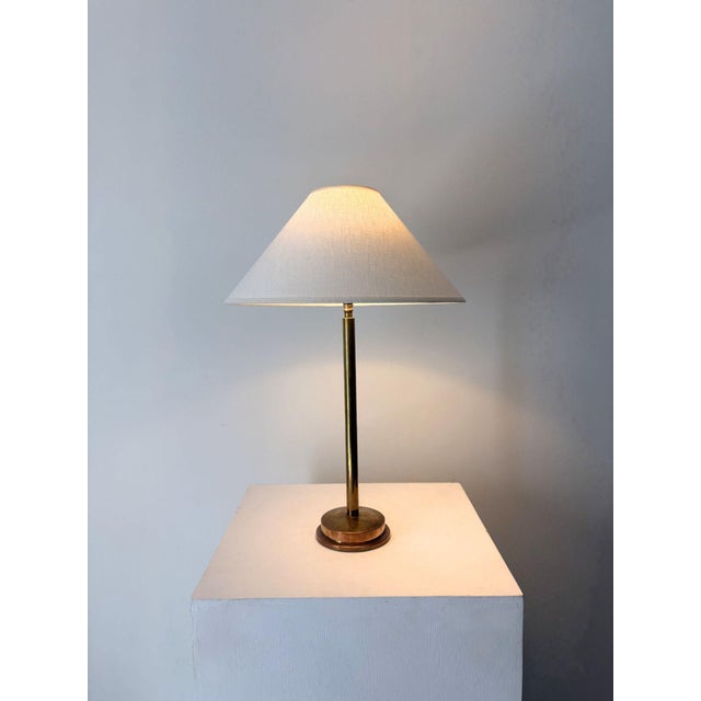 A minimalist 20th century Swedish table lamp. Formed in brass which has acquired a great patina, with a sleek unadorned...