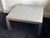This large square coffee table is made of brushed stainless steel and follows a pared-back Parsons form. The top runs...