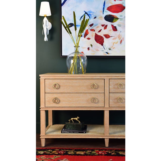 The Richmond cerused oak console has four drawers, an open cane shelf, and brass drawer pulls. Its the perfect addition in...