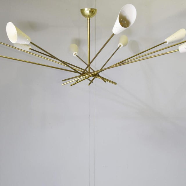 A ten-light chandelier with aluminium shades and a brass frame; its style and shape are reminiscent of the famous 1960s...
