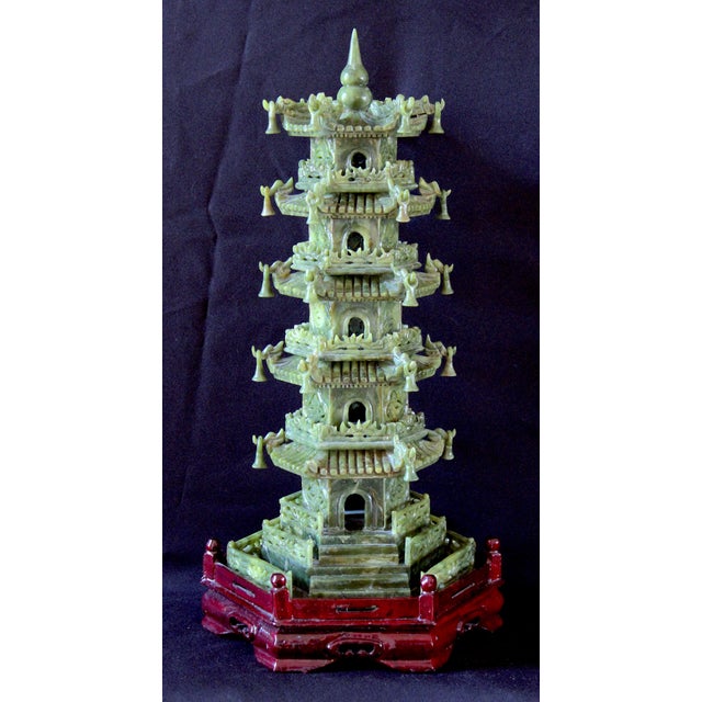 An intricately carved vintage Chinese jade pagoda sculpture, masterfully detailed and presented on a carved red wooden...