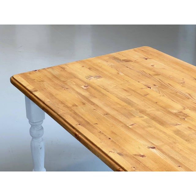 A generously sized dining table in a classic country style with a charming, handcrafted appeal. The white-painted frame...
