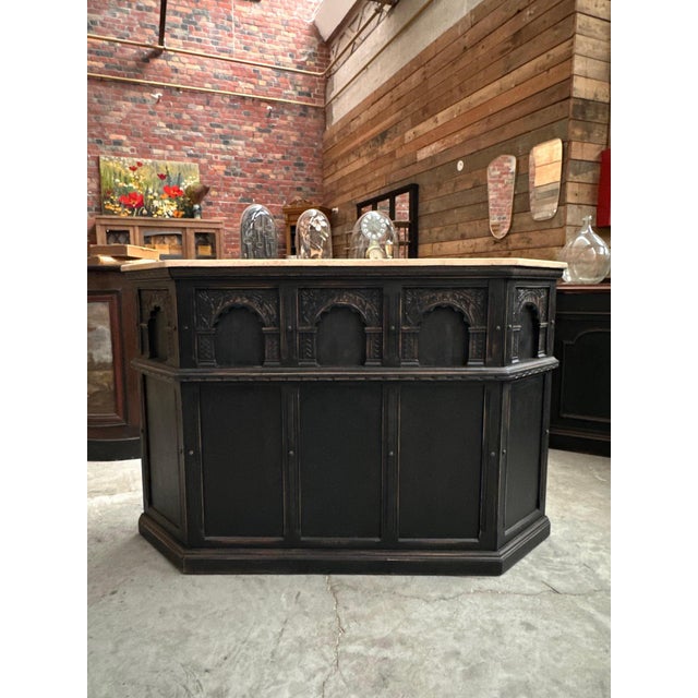 This old oak bar counter has been completely restored. Its black patinated front features carved arch motifs and its top...