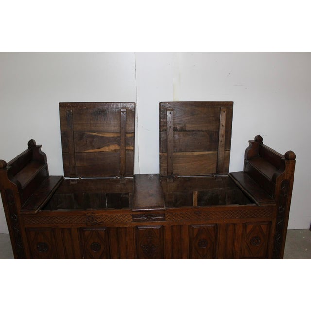 Oak storage bench with a carved front, opening with four drop-leaf doors: two under the seat and two on the sides for...