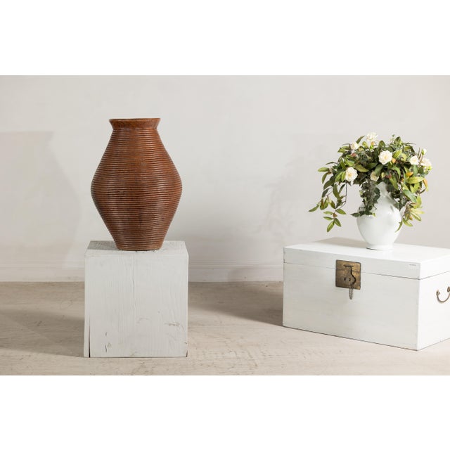 A Thai ribbed vintage pottery vase with burnished surface from the Prem collection with tapering lines wrapped around the...