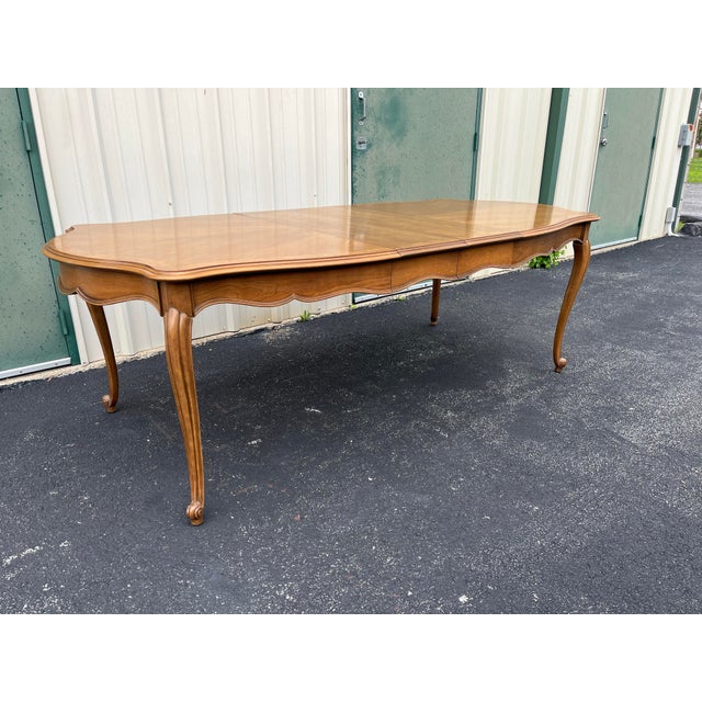 A French country style extension dining table attributed to Century Furniture. Made of fruitwood with burlwood banding,...