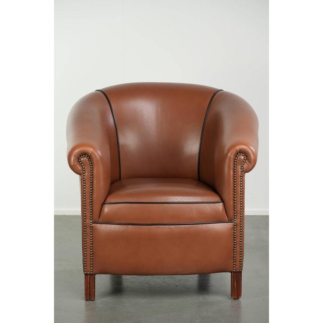 This beautiful English club chair is made of cowhide leather and, thanks in part to its decorative studs, features a...