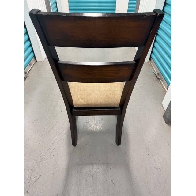 Wooden dining chair featuring a cushioned upholstered seat. • Rich wood finish with a ladder back design • Comfortable...