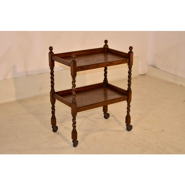Period Edwardian oak bar cart from England, circa 1900. The top of this cart is decorated with hand turned finials,...