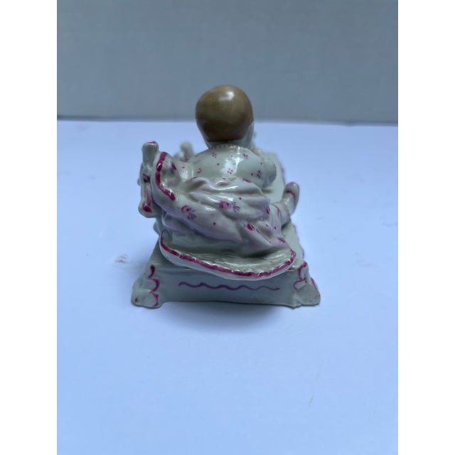 A single antique Victorian porcelain figurine depicting “tug of war” with baby and dog.