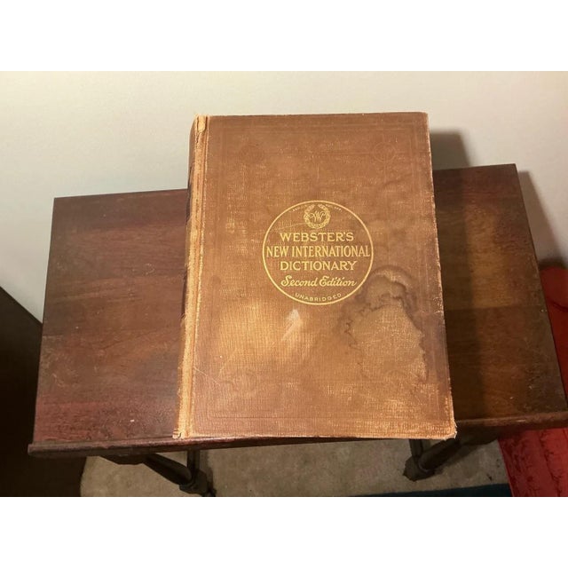 An antique wood stand with a thick top, a lower shelf and turned legs, sized to hold a large dictionary. It comes with a...