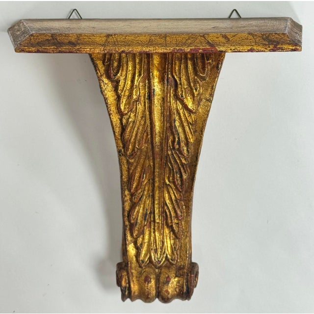 Vintage classic Italian gilt wood wall shelf. Stylized scrolled acanthus leaf base with a clean lined beveled top. Two...