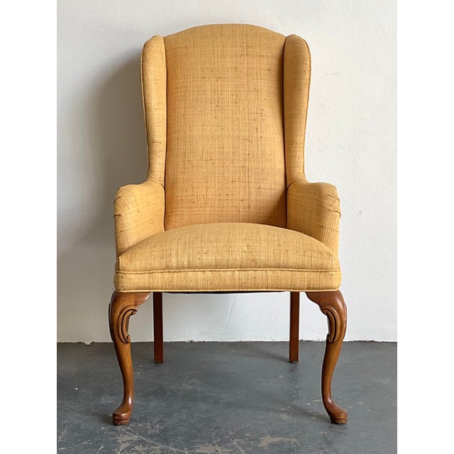 This vintage wingback chair is a masterful blend of classic Queen Anne silhouettes and organic, tactile materiality....