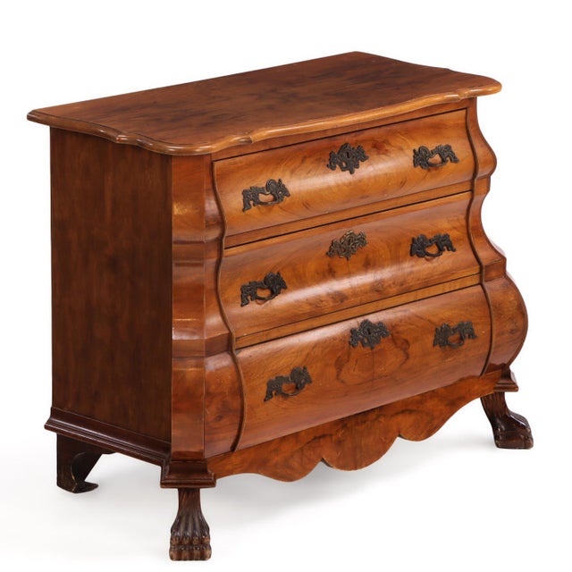 This striking commode features a dramatically shaped double-bombé case crafted from richly figured burr walnut, creating a...