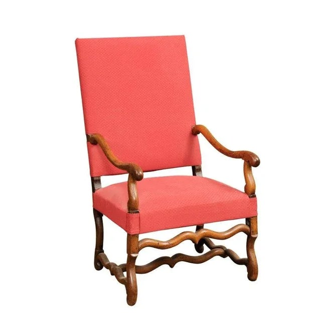 A French Louis XIII style walnut fauteuil from the 19th century, with os de mouton base, large scrolling arms and red...