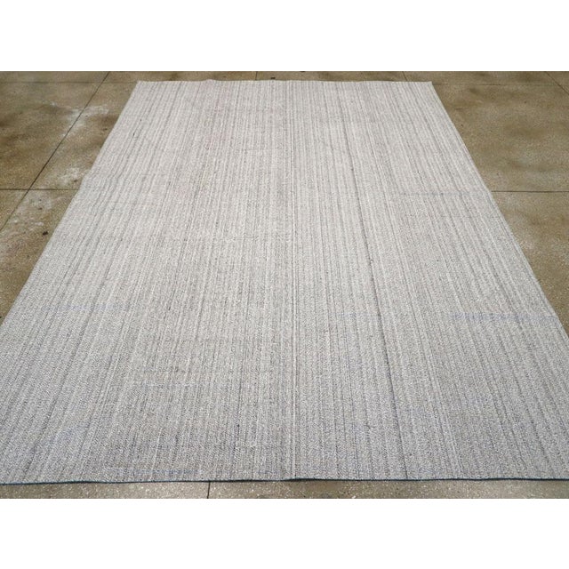 This Mid-20th century Turkish Flatweave Kilim rug, features a refined and minimalist design with delicate vertical...