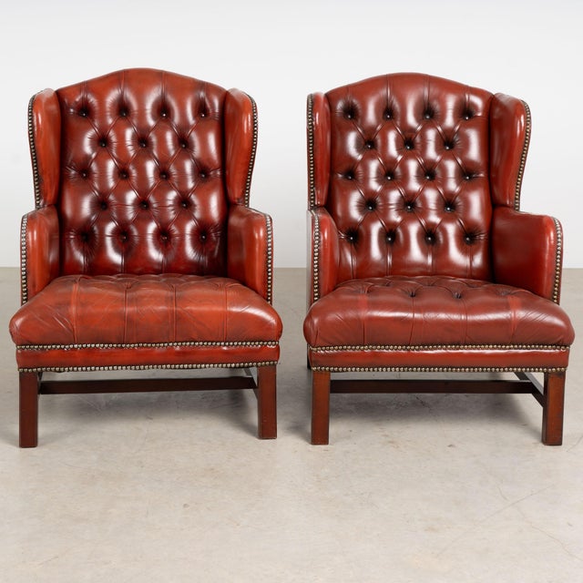 Pair of 20th century Danish Chesterfield wingback club chairs upholstered in vintage tufted leather with a rich reddish-...