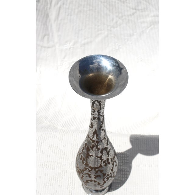 A tall vase from India of silver metal over brass with floral engraved designs. Probably nickel or steel. Striking in...