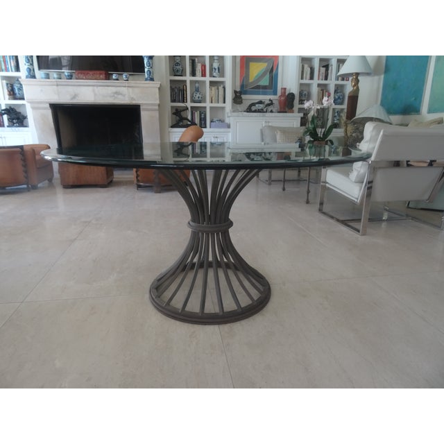 A hand-forged or wrought iron table featuring a thick 3/4-inch beveled glass top embodies the timeless, high-end artisan...