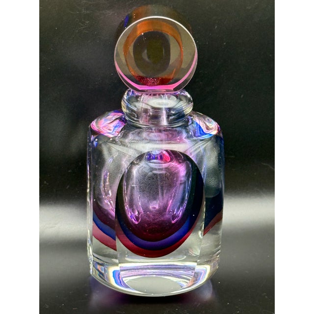 A striking Murano-style art glass perfume bottle featuring a sculptural geometric design and vibrant layers of cobalt...