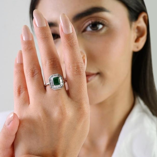 This elegant halo ring features 1 emerald-cut natural green emerald totaling 1.06 carats, set in 14k white gold. The...