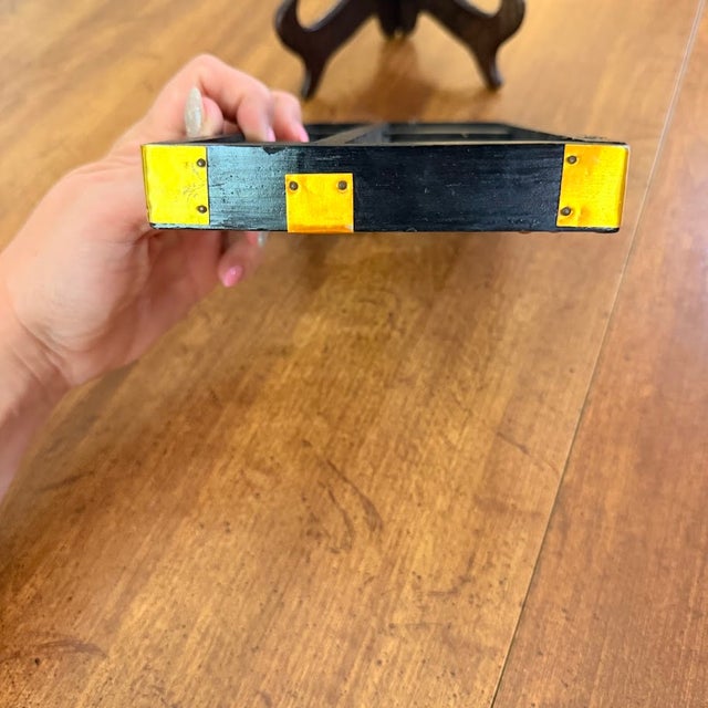 Vintage Chinese suanpan abacus features a black wooden frame with striking red beads and brass-toned hardware accents....