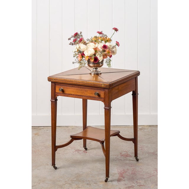 This Edwardian mahogany envelope card table features a square top that unfolds in an envelope style to reveal a green...