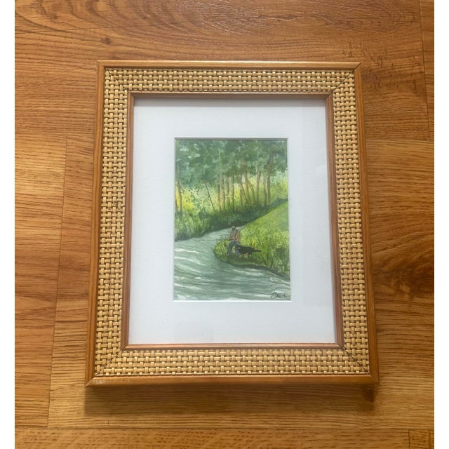 Original watercolor depicting a tranquil woodland stream with a solitary figure and dog paused along the riverbank. Soft...